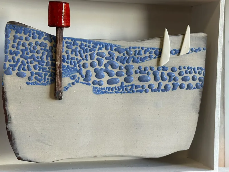 Blue and cream ceramic seascape with two white sails and a red navigation marker
